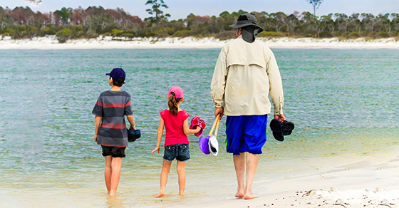 Person walking on beach with two children