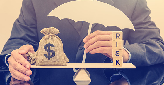 Money and risk on a scale with an umbrella covering risk